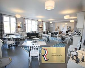 restauracja z białymi krzesłami, stołami i pudełkiem w obiekcie Logis Hôtel & Restaurant Au Clos Paillé Charme & Caractère w mieście La Roche-Posay