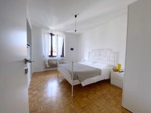 - une chambre blanche avec un lit et du parquet dans l'établissement LovingStresa 2 brand new apartment, à Stresa