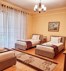 1 dormitorio con 2 camas y lámpara de araña en All Seasons Apartments, en Shkodër
