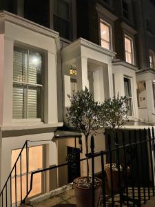 a white house with a tree in front of it at Boutique Barclay House London townhouse - West London, Kensington, Chelsea, Fulham in London +49 photos