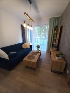 ein Wohnzimmer mit einem blauen Sofa und einem Tisch in der Unterkunft APARTAMENT PRESTIGE OŚWIĘCIM in Oświęcim