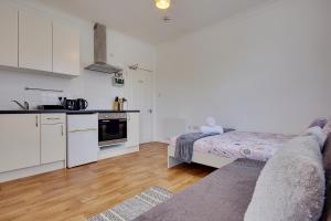 a kitchen with white cabinets and a bed in a room at Heron Court Holiday Apartments in Bournemouth