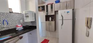 a kitchen with a white refrigerator and a phone at Apartamento Mobiliado, Parque Atheneu. in Goiânia