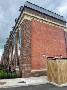 a red brick building with a fence in front of it at Peak Willow Apartments in Leek