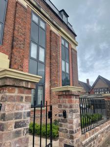 ein Backsteinhaus mit einem schwarzen Zaun davor in der Unterkunft Peak Willow Apartments in Leek