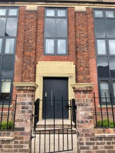 a large brick building with a black door at Peak Willow Apartments in Leek