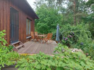 una terraza de madera con mesa, sillas y sombrilla en Ferienhaus Triebesgrund, en Zeulenroda