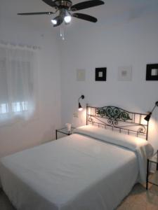 1 dormitorio con 1 cama y ventilador de techo en Apto para Vacaciones con WIFI, en Chipiona