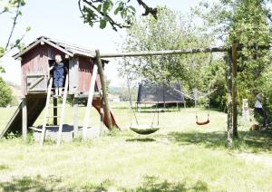 a young boy standing on a swing in a playground at Ferienhof Forstmoar in Gars am Inn