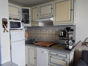 a kitchen with white cabinets and a white refrigerator at studio Batlou ménage inclus in Arette