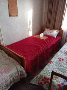 a small bedroom with a bed with a red bedspread at Tirgus iela 2 in Krāslava
