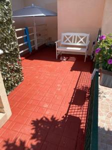 einen roten Backsteinsteg mit einer Bank und einem Regenschirm in der Unterkunft Casa stella marina in Campomarino