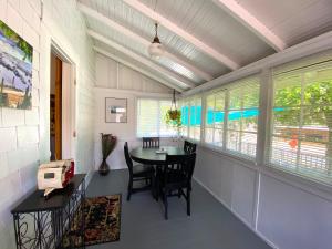 Un comedor con mesa y sillas y ventanas. en Birdwatch Cottage With River Beach Pass, en Three Rivers