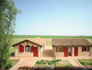 una casa con porte rosse in un campo di Agriturismo Ca' Lealtà a Marango di Caorle – Casa Pace