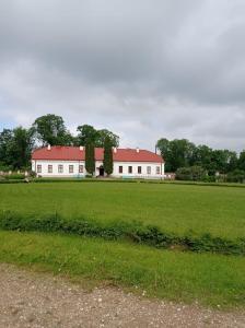 a large white building with a red roof in a field at Tirgus iela 2 in Krāslava