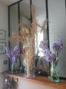 three vases with flowers on a shelf in front of a mirror at clos st Joseph in Oullins