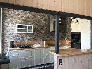 a kitchen with white cabinets and a brick wall at L'Oréline au cœur de la région des Lacs du Jura in Pont-de-Poitte