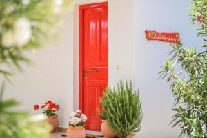 una porta rossa con piante in vaso di fronte a una casa di Therianos Traditional Villas a Kallithea