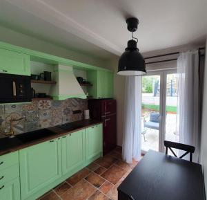 una cocina con armarios verdes, una mesa y una ventana en Apartments Mia 2, en Rovinj