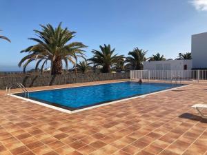 a swimming pool in a resort with palm trees at Kiltankin beag in Costa Teguise