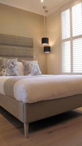 a bedroom with a large bed with white sheets and a window at Boutique Barclay House London townhouse in London