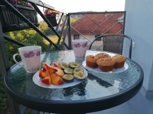 two plates of muffins and cupcakes on a glass table at Apartman San in Vrnjačka Banja