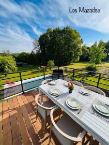 a wooden deck with a table and chairs on a balcony at Les Mazades à 10 min de Périgueux avec piscine chauffée, meublé de tourisme classé 3 étoiles in Annesse-et-Beaulieu