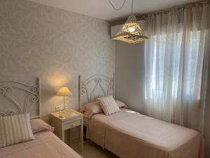 a bedroom with two beds and a chandelier at Velilla Apartment “Sun&Sea” in Almuñécar