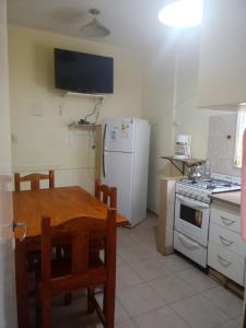 cocina con mesa y nevera blanca en Departamento 4 ambientes para 5 personas 1 cama doble y una cucheta de 3 en Mar del Plata