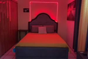 Un dormitorio con una cama con luces rojas. en Relaxing Tropical Studio, en San Juan