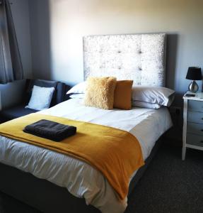 a bedroom with a bed with a yellow blanket on it at The Tree-house B&B in Ballymena