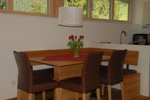tavolo da pranzo con sedie e vaso di fiori di Apartments Bischof a Schröcken