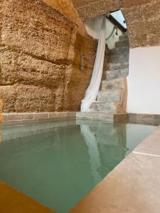 una piscina de agua frente a una pared de piedra en CORTE LARGO LAURO DIMORE & SPA en Gemini