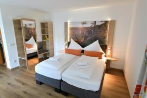 Schlafzimmer mit einem Bett mit weißer Bettwäsche und orangefarbenen Kissen in der Unterkunft Landhotel zum Raben in Kipfenberg