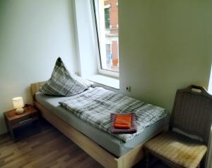 a bed in a room with a window and a chair at Ferienwohnung Karsten - nahe Chemnitz in Limbach - Oberfrohna