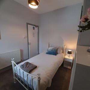 a small bedroom with a bed and a lamp at Merginn Guest House in Blackpool