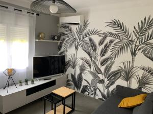 ein Wohnzimmer mit einem Wandbild von Palmen in der Unterkunft Explore the World 2 in Perpignan