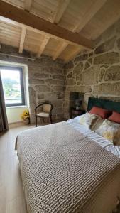 a bedroom with a large bed in a stone building at Casinhas da eira caramulo turismo rural in Arca