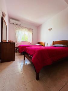 two beds in a room with red sheets and a window at Vila Flora in Santa Bárbara de Nexe