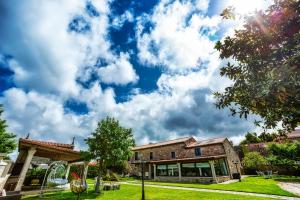 un edificio de ladrillo con un cielo azul con nubes en Casa de Lema Boutique, en Muxía