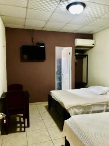 a bedroom with two beds and a tv on the wall at Black Lion Inn in Santiago