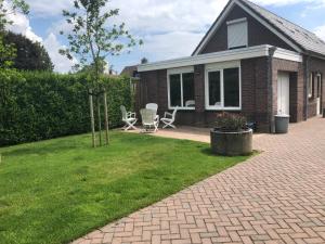 a brick house with a patio and chairs in the yard at De Zolder in Meterik