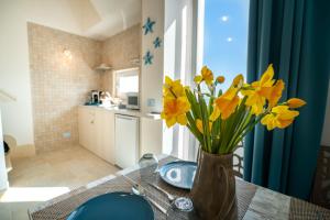 a vase of yellow flowers on a table in a kitchen at Donnamaria - Dimora Vista Mare in Polignano a Mare +17 photos