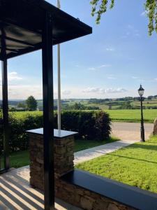 a view from the porch of a house with a stone fireplace at Tiny House - Luxury Cottage in Bullange