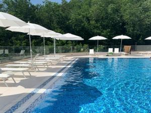 a swimming pool with white umbrellas and chairs and a swimming pool at Comfort studio with sea view and swimming pool in Becici