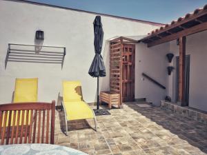 - une terrasse avec 2 chaises jaunes et un parasol dans l'établissement Casa en La Ladera - Real vibe - Beach & Mountain, à San Nicolás