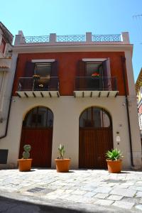 a house with three doors and potted plants in front of it at Isula in Palermo