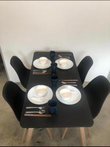 a table with black chairs and white plates and chopsticks at Kota Permai Mini Rest Room 99 Full Equipped in Bukit Mertajam +14 photos