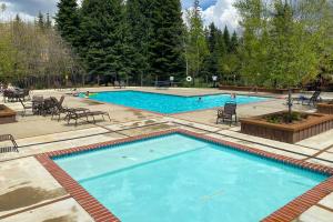 a large pool with blue water and chairs and trees at Family-Friendly McCall Cabin Pool Access and Bikes in McCall