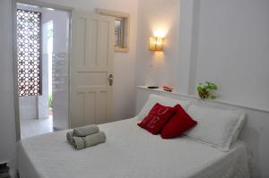 une chambre avec un lit avec deux oreillers rouges dessus dans l'établissement Suítes Recanto cama e café, à Arraial do Cabo 12 autres photos